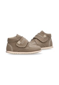 Zapatos de cuero marrón blandos para niños pequeños, con correas de Velcro, costuras blancas y suelas de goma flexibles y de color claro.
