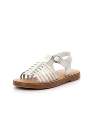 Sandalias de cuero blanco con diseño trenzado, de punta abierta, correa para el tobillo y hebilla de metal. Suela de goma marrón claro. Textura suave, estilo minimalista.