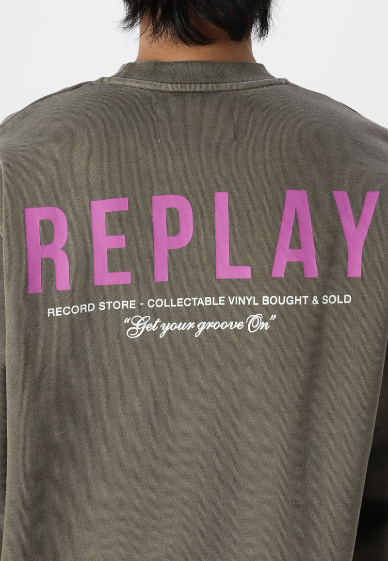 Olivgrüner Sweatshirt mit auffälligem lila Schriftzug "REPLAY" und weißen Phrasen über einen Plattenladen, die auf der Rückseite gedruckt sind. Weicher Stoff.