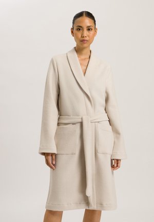Robe beige mi-longue en tissu texturé. Dotée d'un col châle, de poches avant et d'une ceinture à nouer. Fini lisse et doux.
