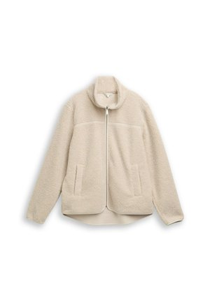 Veste en polaire beige avec un col haut, fermeture éclair et deux poches avant, présentant une texture douce et un ourlet légèrement arrondi.