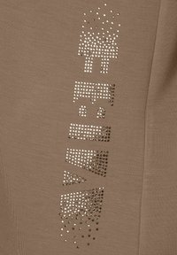Brown fabric shirt featuring a design of metallic studs arranged in geometric shapes on the front, creating a textured visual detail.