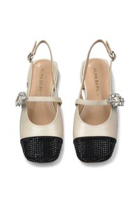Scarpe slingback in pelle beige con punta nera intrecciata, dotate di una fibbia decorativa in cristallo sulla cinghia e un design a punta aperta arrotondata.