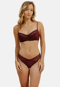 Ensemble de lingerie bourgogne avec des accents en dentelle. Le soutien-gorge dispose de bretelles réglables et d'un bord festonné ; les culottes ont une coupe taille basse avec des panneaux en dentelle décoratifs.