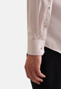 Camicia button-up rosa chiaro con piccolo motivo a quadri blu navy e borgogna. Manica con polsino e chiusura a bottone, dettagli ricamati sul polsino.