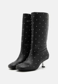 Mustad kuni põlveni saapad, mis on valmistatud sileda materjali eest, kaunistatud hõbedaste nupudega, terava varbaga ja väikese metallse varbaga.