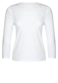 Vit långärmad topp med en texturerad stickad mönster över axlarna. Mjuk tyg med en klassisk rund halsringning och rak fåll.
