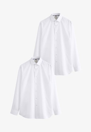 Dwie proste białe koszule z długim rękawem i kołnierzykiem, na białym tle.