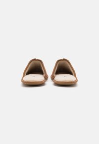 Brown fabric slippers with a soft, cream-colored lining; open design and rounded toe shape; flat soles for indoor use.