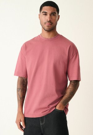 Kortærmet t-shirt med rund hals i vasket rosenfarve, lavet af bomuld, med en afslappet pasform og synlige sømdetaljer.