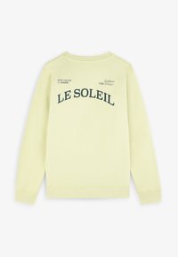 Sweat-shirt jaune clair à col rond. Présente un texte imprimé noir : "LE SOLEIL" et des accents de texte plus petits, des poignets et un ourlet côtelés.