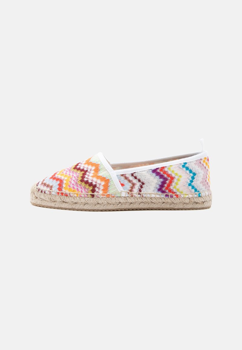 Espadrille colorée à motifs zigzag, slip-on, avec semelle en jute tressé et bordure blanche, sur un fond clair uni.