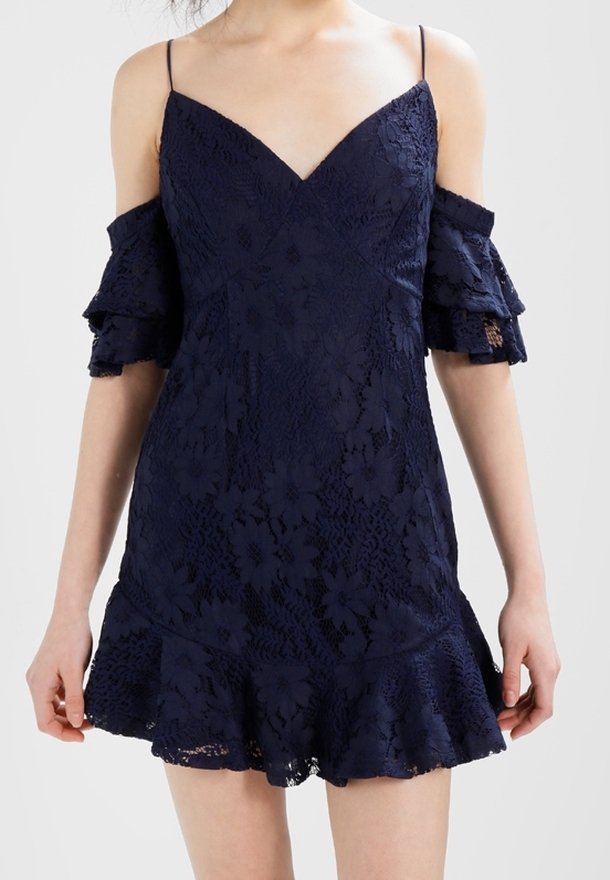 Robe en dentelle marine avec design épaules dénudées, décolleté en V, manches à volants et ourlet évasé. Présente des motifs floraux sur toute la surface.