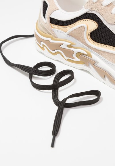 Sneaker med övre del i svart mesh, beige mockadetaljer, vita inslag och en kurvig gummisula med flam-mönster; inkluderar svarta snören.