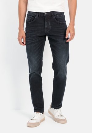 Dark blue denim jeans with a slim fit, featuring five pockets, subtle fading, and a button closure, paired with white sneakers.