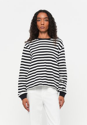 Zwart-witte gestreepte langemouwen shirt met een ronde hals en elastische manchetten, gedragen over witte broek. Heeft een relaxte pasvorm en een zachte textuur.