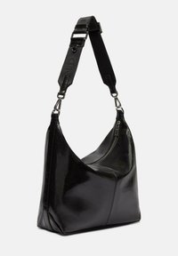 Czarna skórzana torebka o zaokrąglonym kształcie, z metalowym zamkiem błyskawicznym i odpinanym paskiem. Gładka faktura z minimalnymi akcentami.