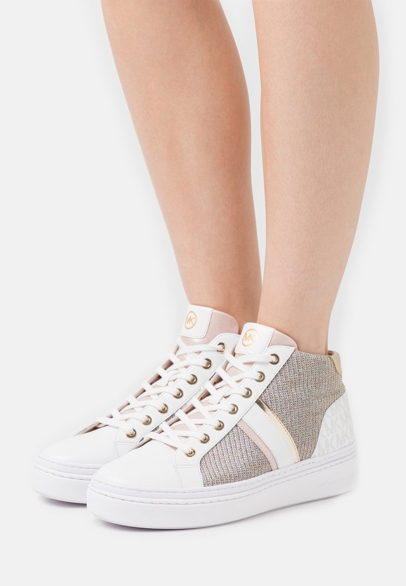 Baskets montantes présentant une base en cuir blanc avec des accents en tissu gris, des détails en métal doré, et un design texturé à l'arrière.