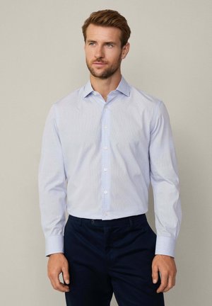 Lichtblauwe button-up shirt met een geruit patroon, lange mouwen en een kraag. Gecombineerd met donkerblauwe broeken. Glad textuur.