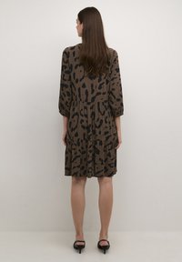 Rochie cu imprimeu de leopard maro, cu manșete bulinate, fustă în straturi și accente negre. Material neted cu o textură moale, design până la genunchi.