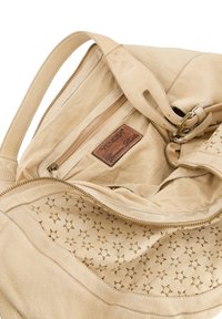 Beige leren handtas met een gestructureerde buitenkant, een interne ritsvak en een gevoerde binnenkant met een patroon van kleine stervormen.