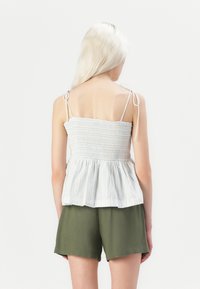 Lysstripet peplum-topp med smock-bodice, tynne justerbare stropper, brukt med olivengrønne shorts. Mykt bomullsstoff.