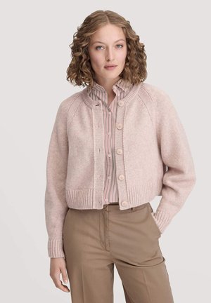Hellrosa gestrickte Strickjacke mit rundem Ausschnitt, geripptem Saum und sechs Knopfverschlüssen, getragen über einer gestreiften Bluse in Pink und Weiß.