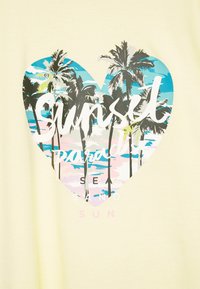 T-shirt amarelo com um gráfico em forma de coração, palmeiras, cenário de praia e o texto "Sunset Paradise" em branco e rosa.