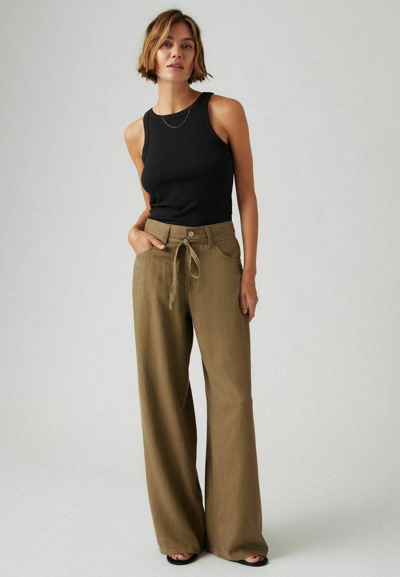 Un débardeur noir à côtes assorti à un pantalon olive décontracté à taille haute, doté d'une taille à cordon et de poches latérales.