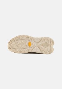 Vibram-pohja, jossa on monisuuntaiset lugs, beige väri, teksturoitu pinta ja upotettu logo pidon ja kestävyyden takaamiseksi.