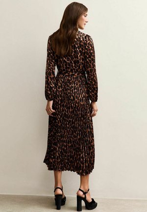 Un abito a maniche lunghe con stampa animale in marrone e nero, caratterizzato da un design plissettato e una vita strizzata, abbinato a sandali neri con tacco.
