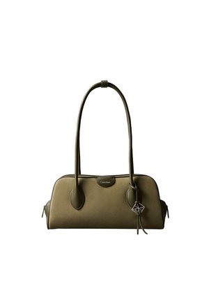 Olijfgroene Calvin Klein handtas met lange handvatten, rechthoekige vorm en een kleine decoratieve bedel die aan één handvat hangt.