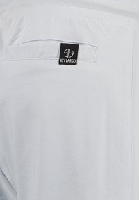 Helle graue Shorts aus weichem Material mit einer einzelnen Gesäßtasche und einem schwarzen "KEY LARGO"-Label. Elastischer Bund für zusätzlichen Komfort.