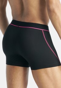 Pantaloni sportivi neri con una linea di accento rosa lungo la vita e i lati, dotati di una vita a coste per un maggiore comfort.