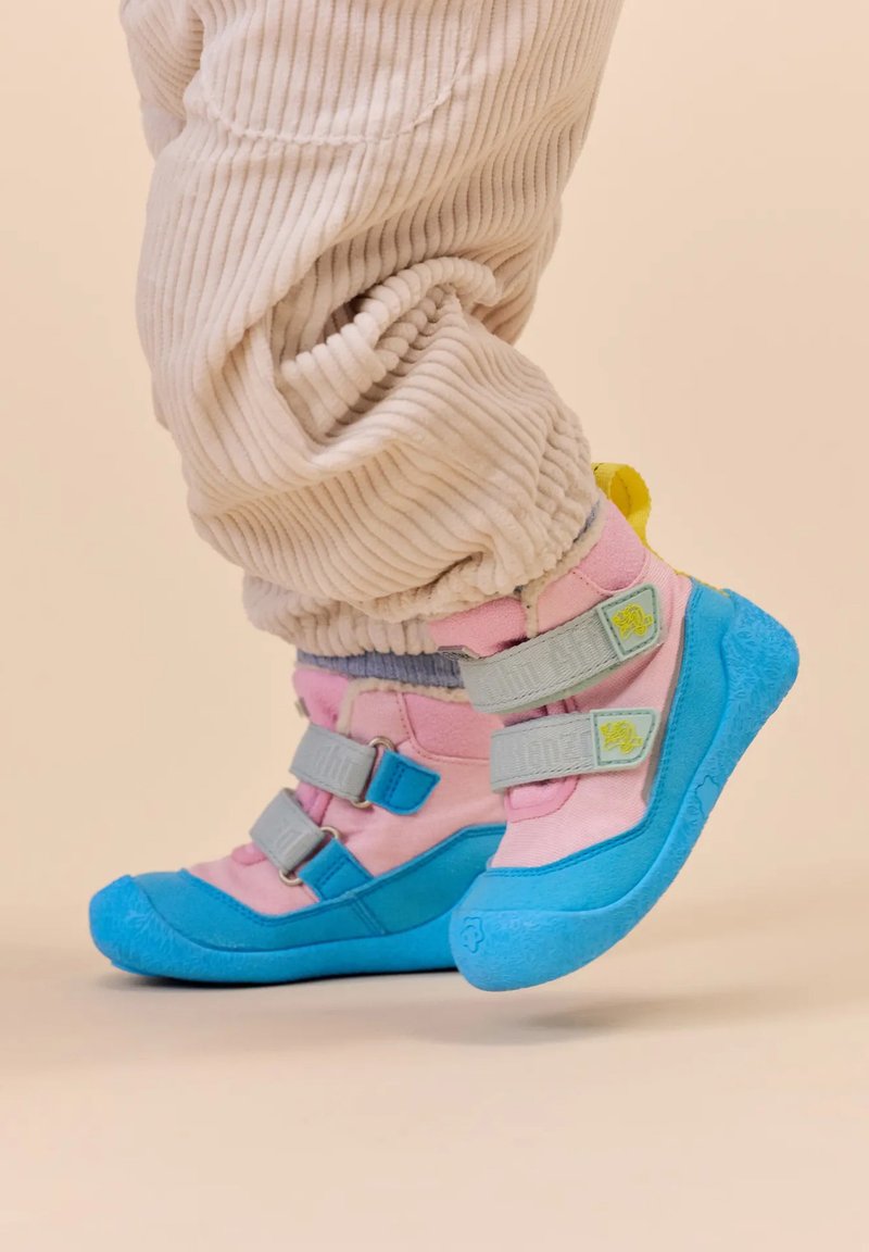 Kleurvolle schoenen met een blauwe rubberen zool, een bovenwerk van roze en blauwe stof, verstelbare grijze banden en een gele hielstrip.