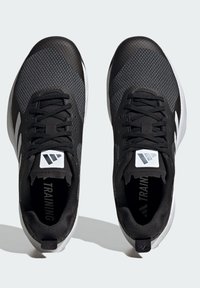 Zwarte sportschoenen met een bovenwerk van mesh, witte accenten, ronde neus, platte veters en een gewatteerde tong met een logo. Gedetailleerde structuur van de outsole.