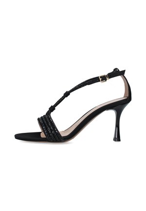Sandalo nero con tacco alto, cinturino a T sottile, dettagli glitterati, punta aperta e chiusura con fibbia dorata alla caviglia.
