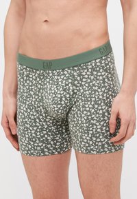 Zaļi bokseri ar ziedu rakstu un mīkstu elastīgu jostu, kuriem ir ērta pieguve un gluda tekstūra. Zīmola logotips uz jostas.