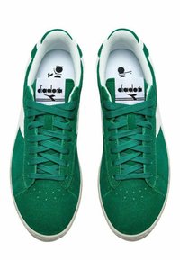 Sneaker in suede verde con accenti bianchi, dotate di un design con lacci, punta rotonda e logo sulla linguetta. Parte superiore testurizzata e suola in gomma.