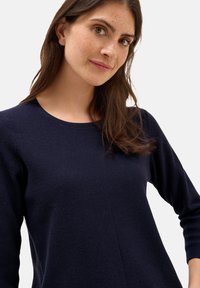 Mörkblå texturerad tröja med rund halsringning och långa ärmar, med ett subtilt våffelstickat mönster.