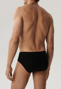 Czarne kąpielówki wykonane z elastycznego materiału. Charakteryzują się gładką teksturą oraz elastycznym pasem, zaprojektowane z myślą o komforcie i dopasowaniu.