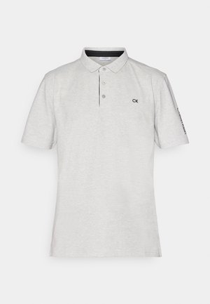 Lys grå polo skjorte lavet af blødt stof. Har en tre-knaps placket og en sort broderet logo på brystet og ærmet. Korte ærmer.