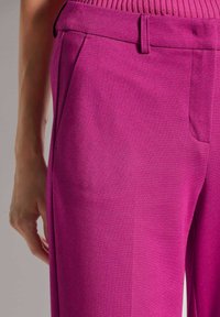 Fuchsialehne Hosen mit glatter Textur, seitlichen Taschen und taillierter Passform. Der Bund ist gerippt für zusätzlichen Komfort.