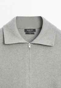 Light gray knit zip-up sweater with a collar, featuring a black Massimo Dutti label inside the neckline.