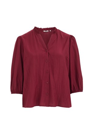 Blouse bordeaux boutonnée avec manches ballon trois-quarts et col volanté sur fond blanc.