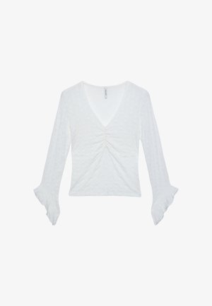 Haut blanc à manches longues avec un col en V, un détail froncé au centre et des manches évasées. Tissu texturé. Aucun motif ou accent visible.