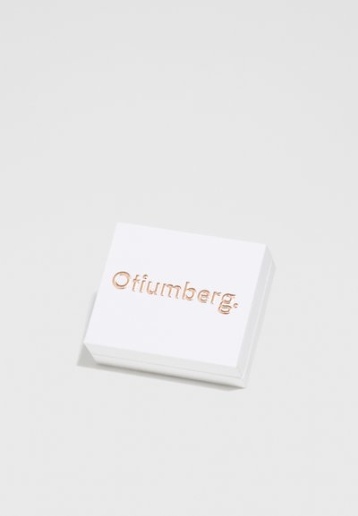 Hvid rektangulær æske med præget rosaguld "Otiumberg" tekst på toppen. Glat overflade, let afrundede kanter, minimalistisk design.