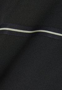 Tela negra con un tejido texturizado, que presenta una franja en blanco a contraste que corre horizontalmente a lo largo de la superficie.