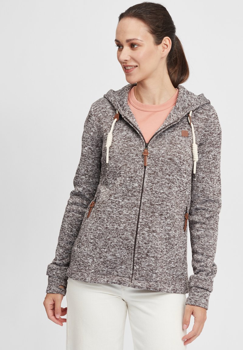 Brun marmoriserad zip-up hoodie med dragkedja och huva, krämfärgade accenter, läderdetaljer och sidofickor, tillsammans med en persikofärgad skjorta.