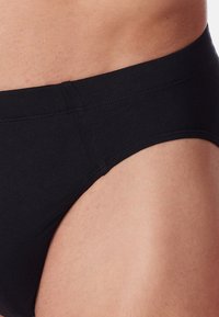 Boxer neri realizzati in tessuto morbido, caratterizzati da una cintura elastica e una finitura liscia, con una vestibilità aderente sulla pelle.